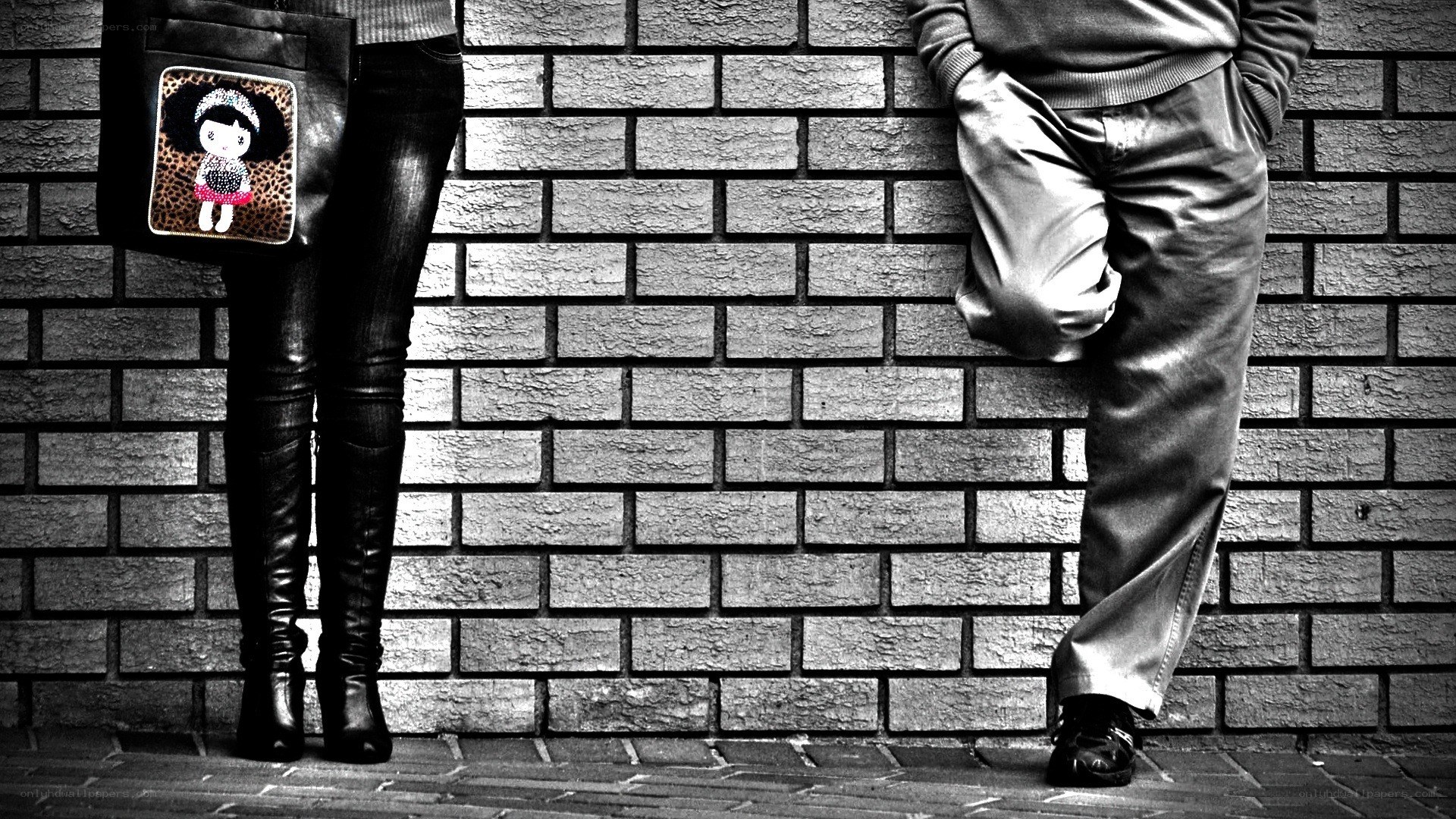 two people standing by a brick wall