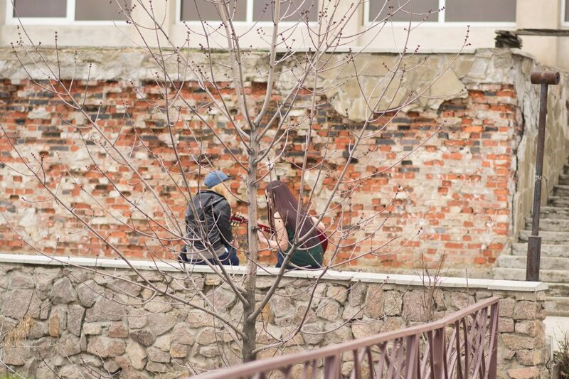 Two people with guitars by a tree