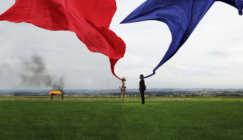 Two people with large flags in a field
