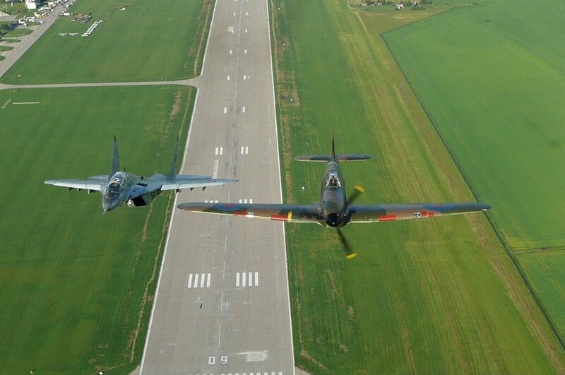 Two planes flying over a runway