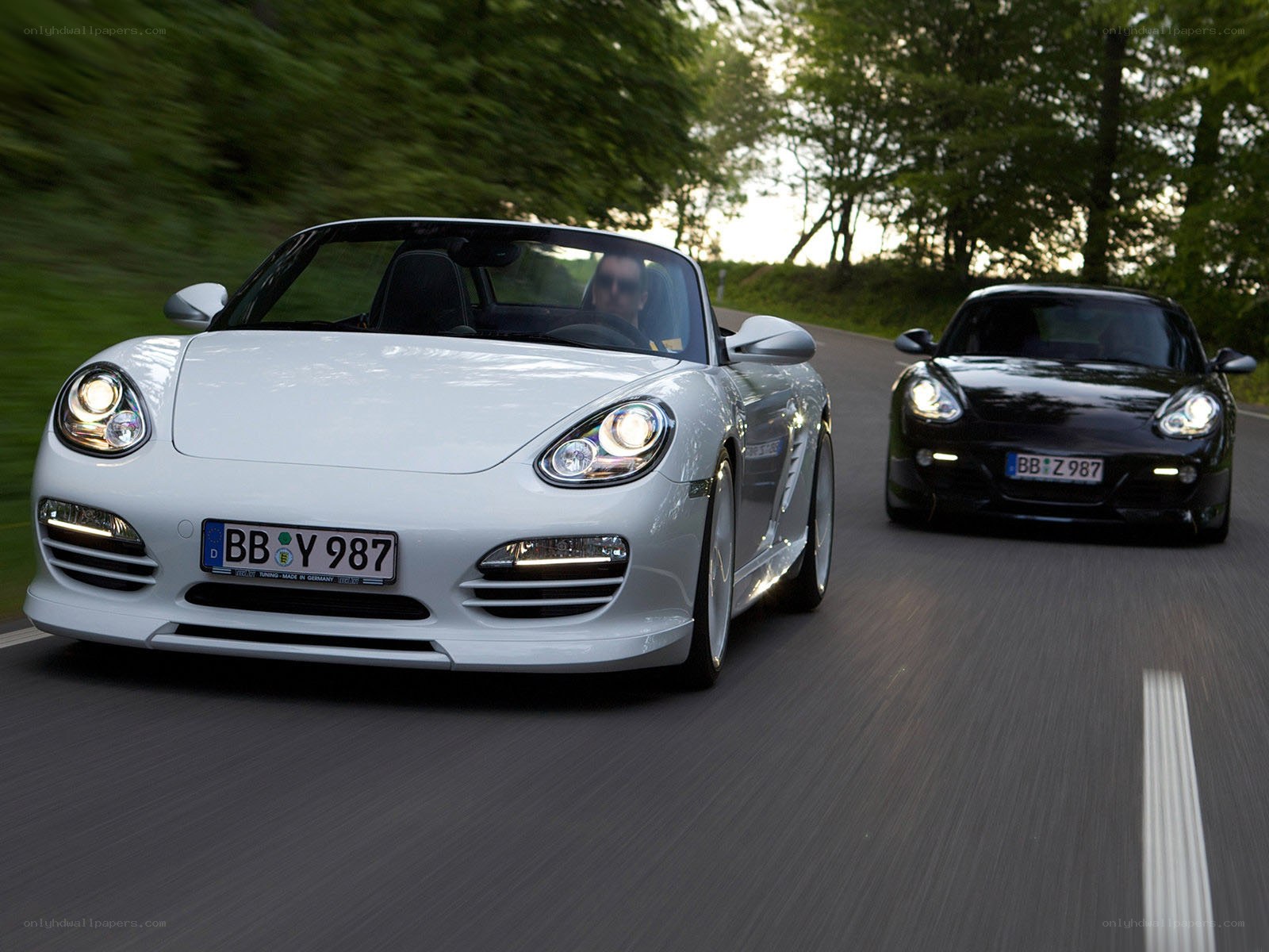 Two Porsche Boxsters on a road