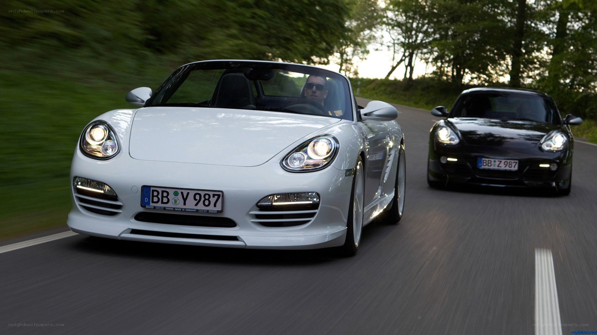 Two Porsche Boxsters on a road