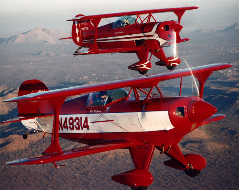 Two red biplanes in flight