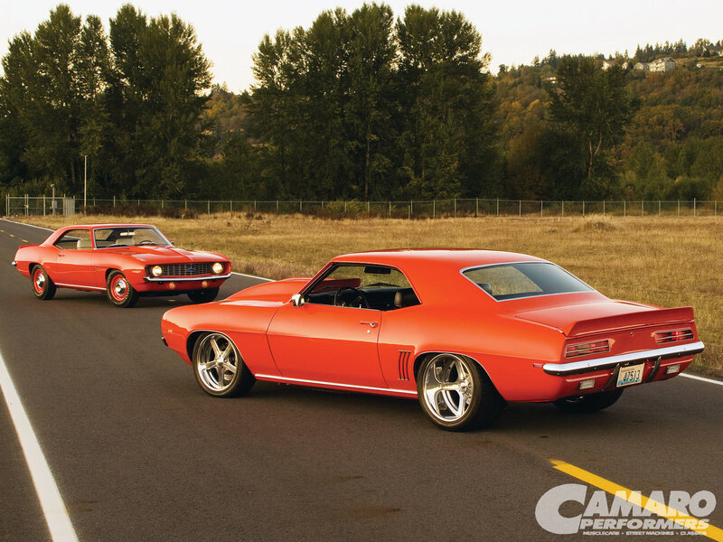 Two red Camaros on a road