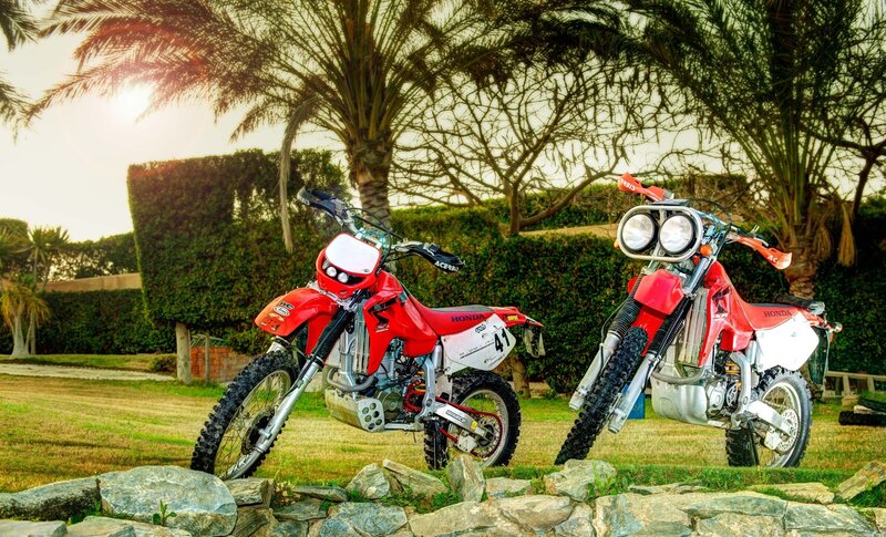 Two red dirt bikes on grass