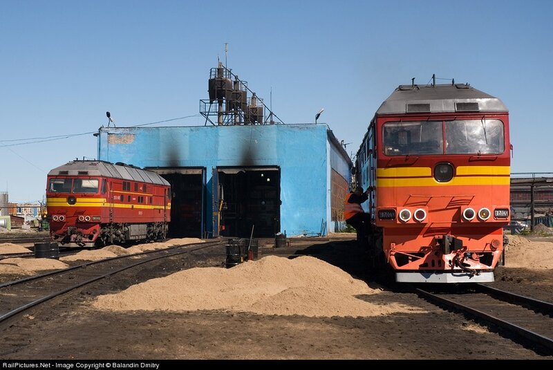 Two red locomotives at a rail yard