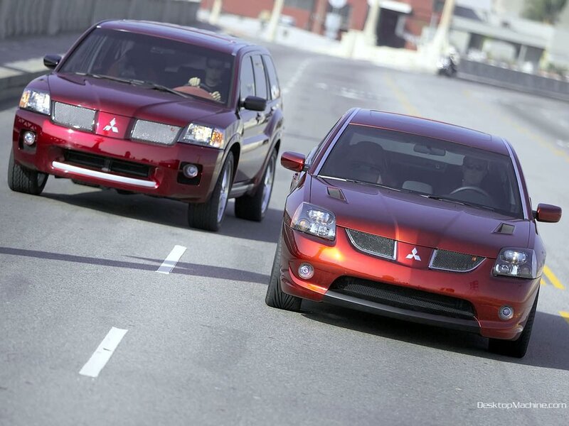Two red Mitsubishi cars on road