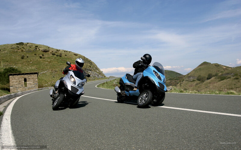 Two riders on scooters on a winding road