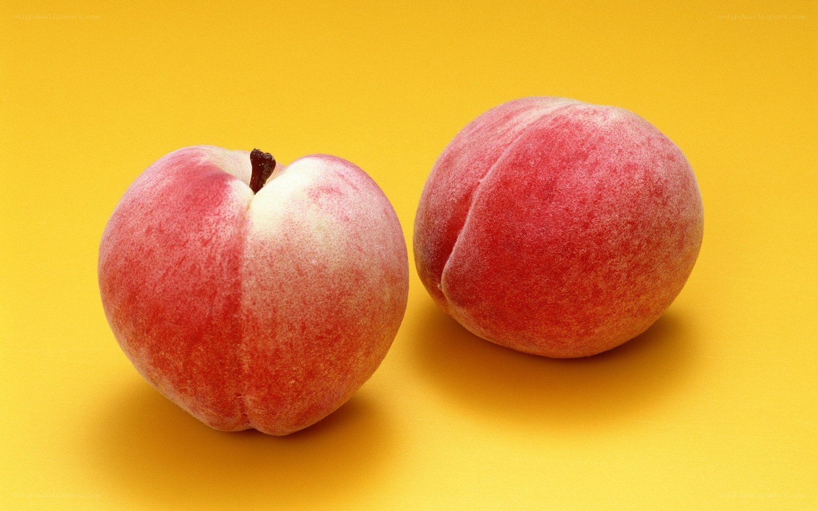 two ripe peaches on yellow