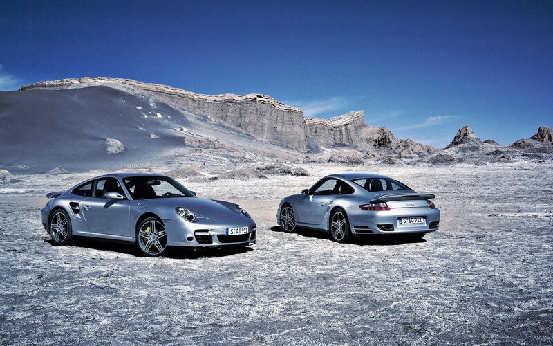 Two silver Porsche cars in desert