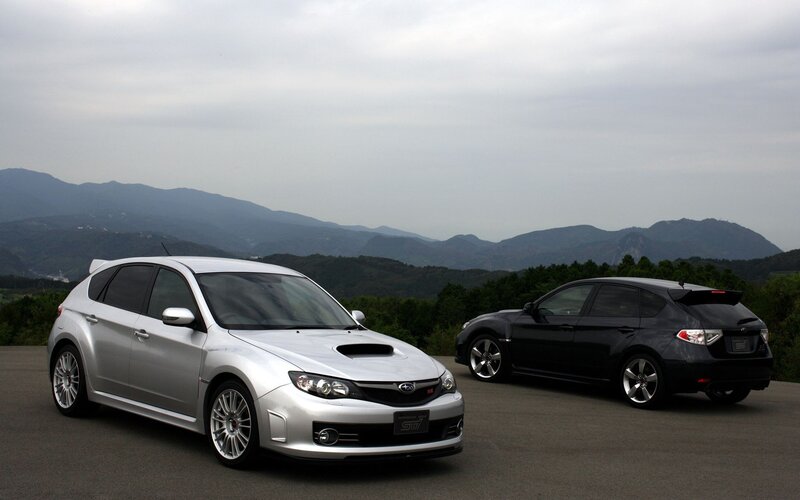 Two Subaru STI cars on a mountain road