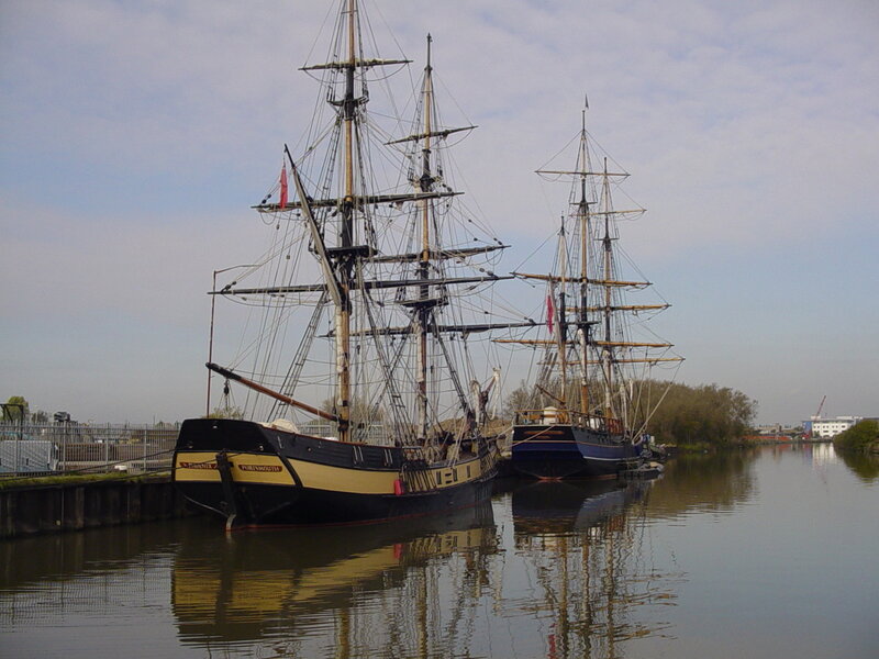 Two tall ships docked at a harbor