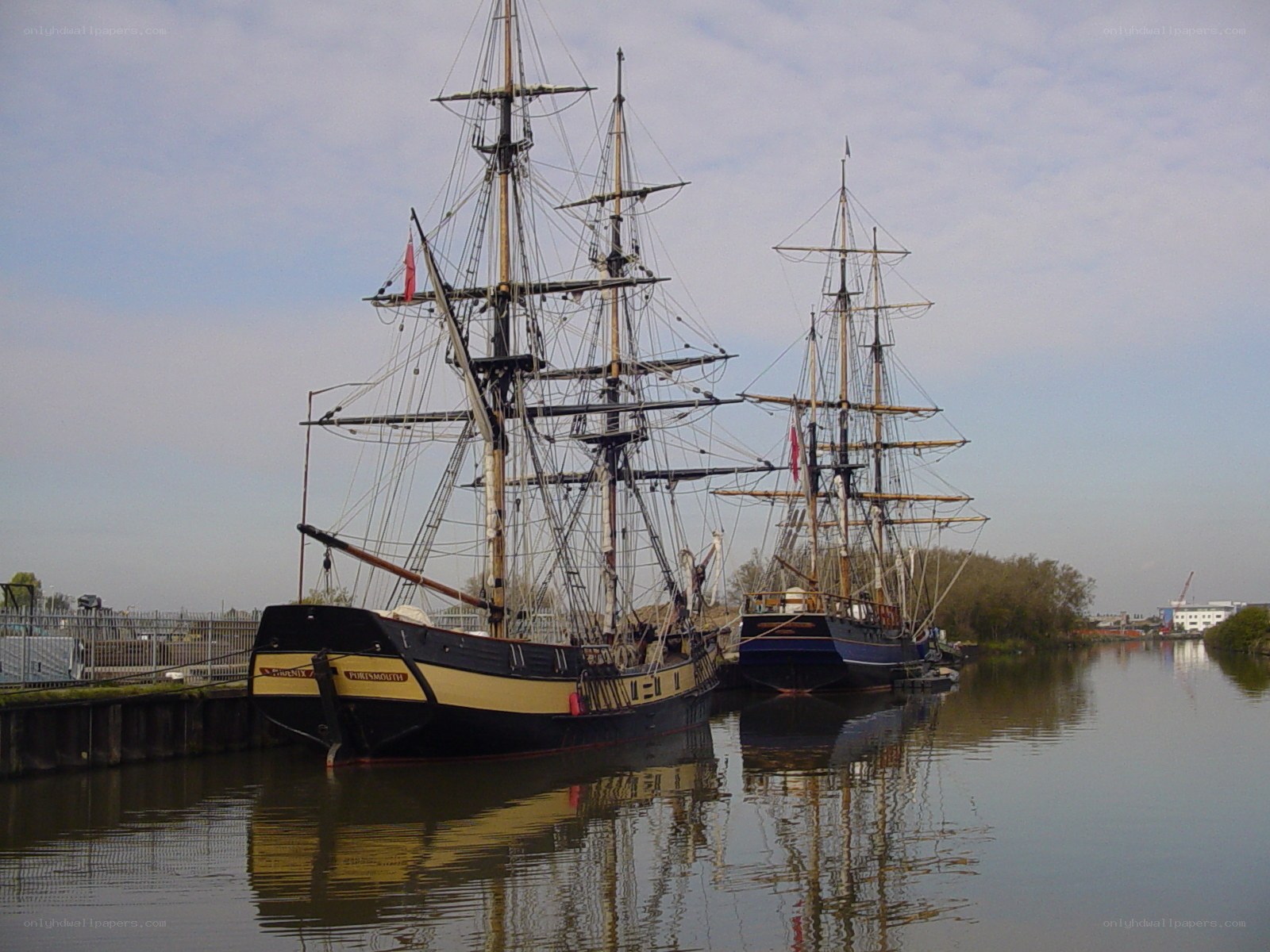 Two tall ships docked at a harbor
