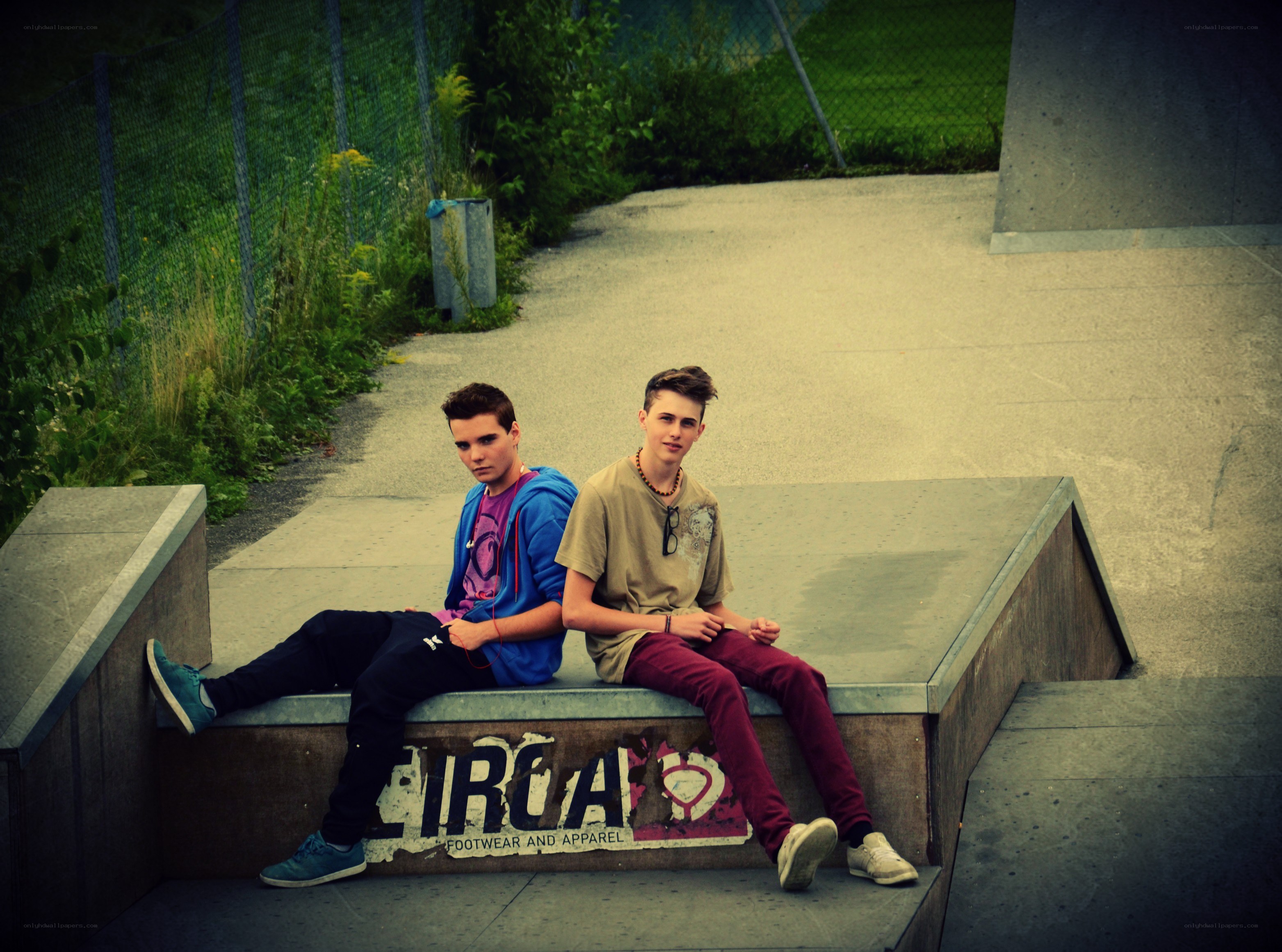 Two teens sitting on a ramp
