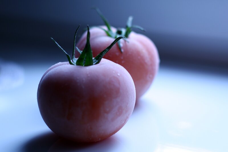 Two tomatoes on a white surface