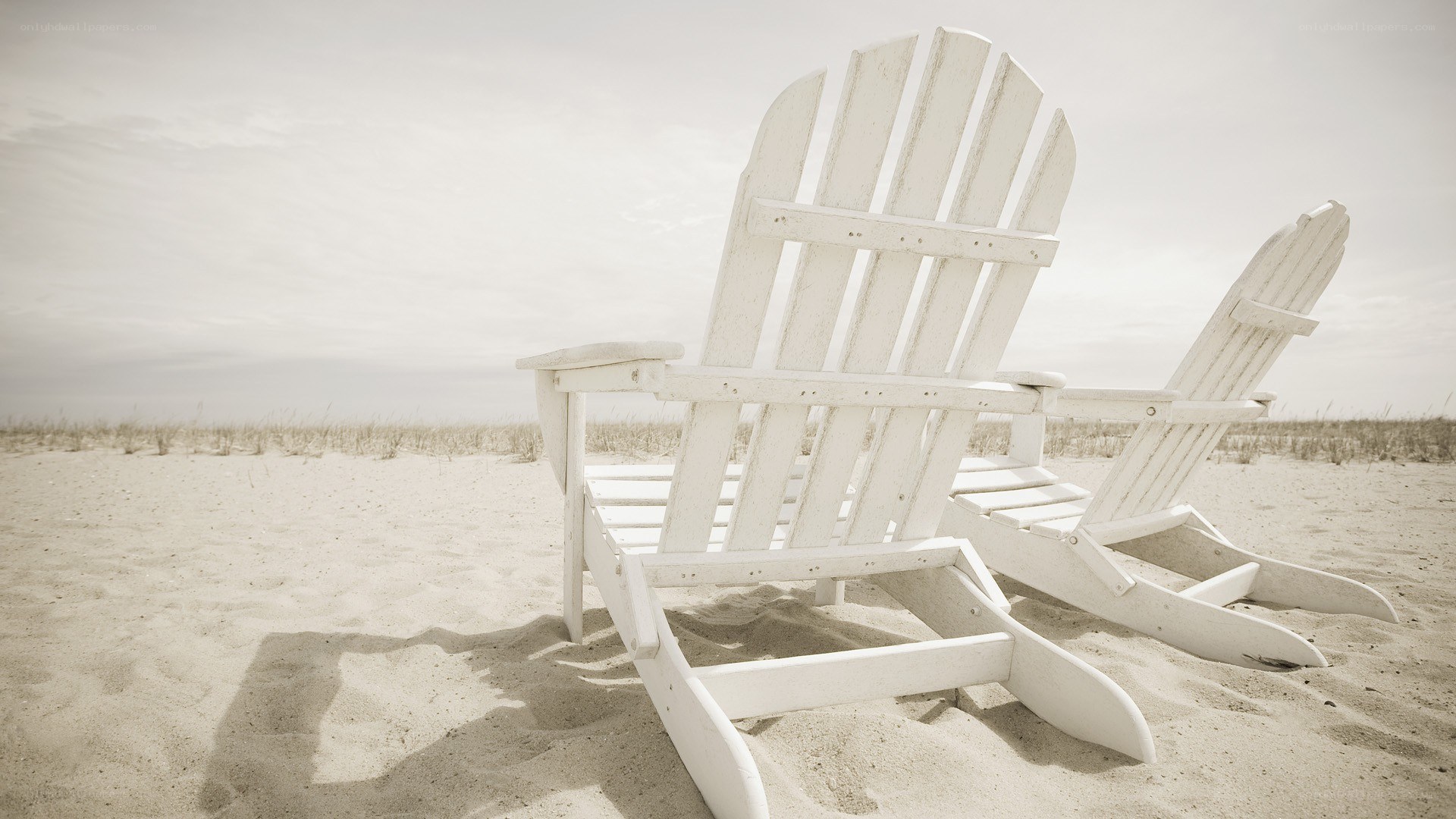 Two white chairs on a beach