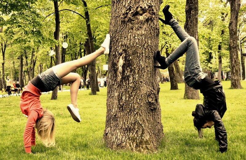 Two women doing handstands in a park