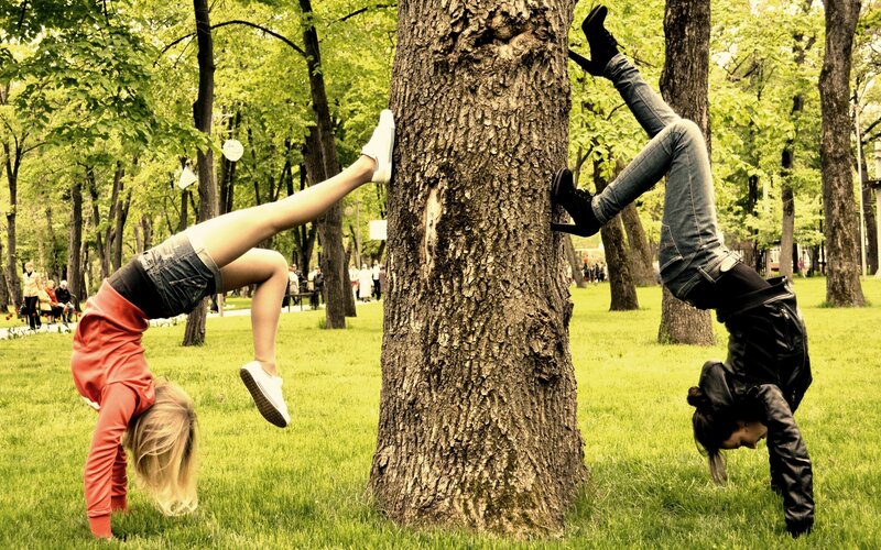 Two women doing handstands in a park