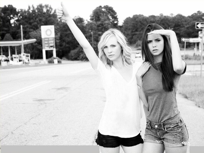 two women hitchhiking on road