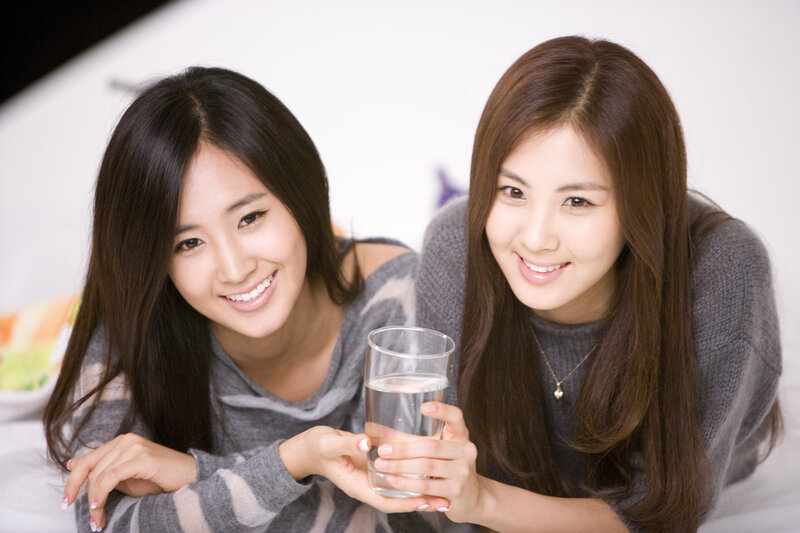 two women holding a glass of water