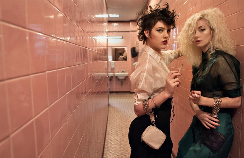 Two women in a pink-tiled restroom