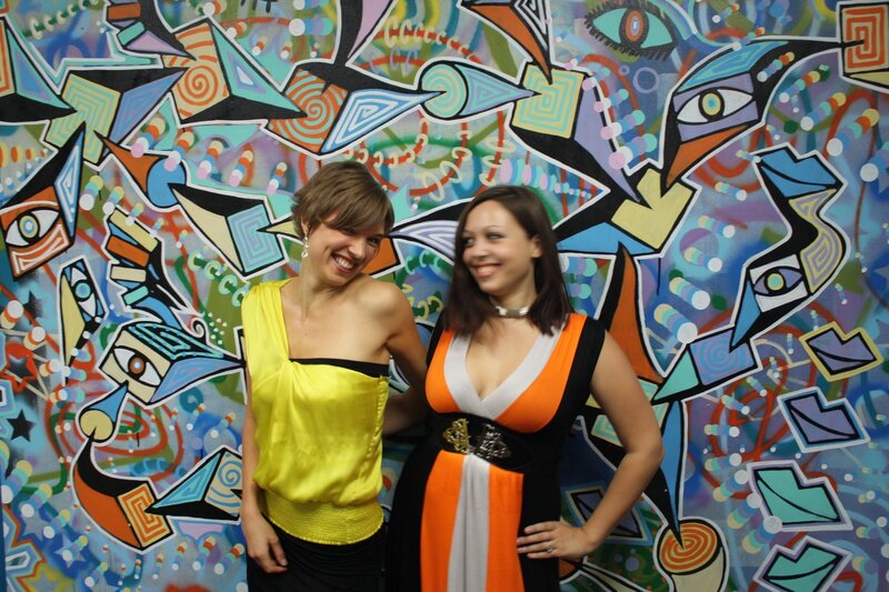 Two women in front of colorful mural