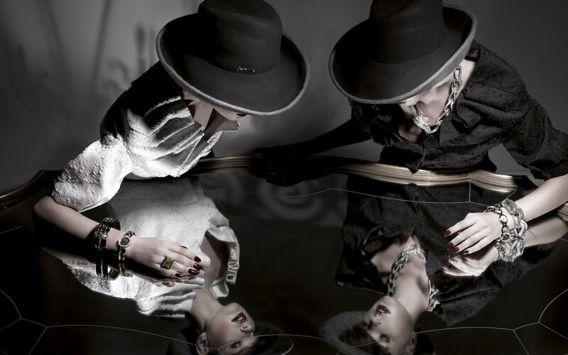 Two women in hats at a reflective table