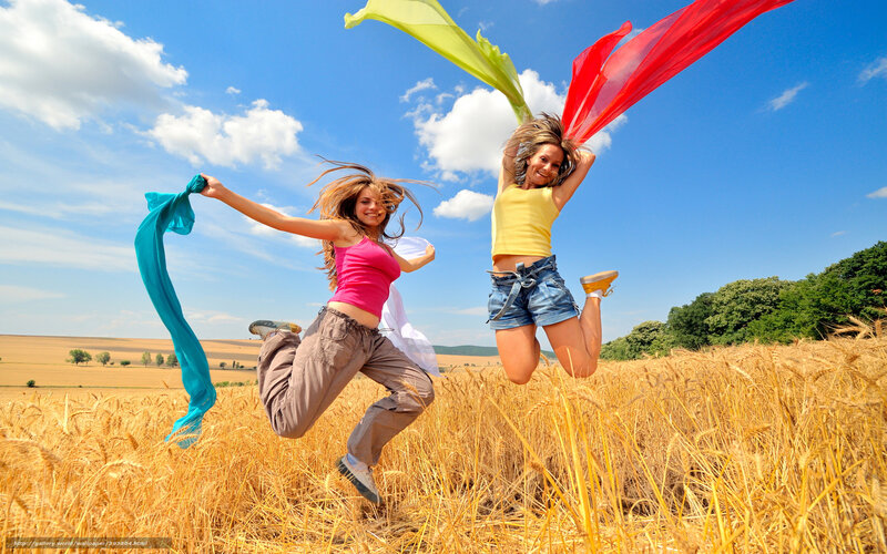 Two women jumping in a wheat field