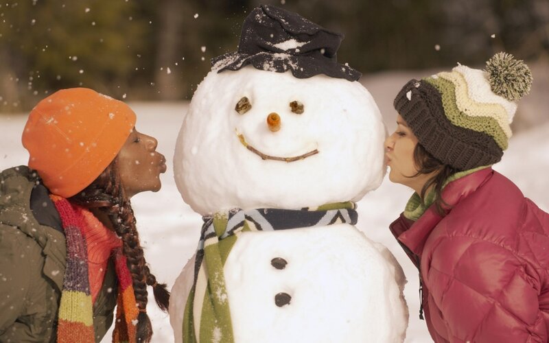 two women kissing a snowman