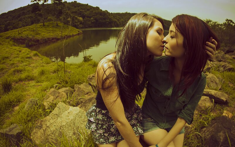 Two women kissing by a lake