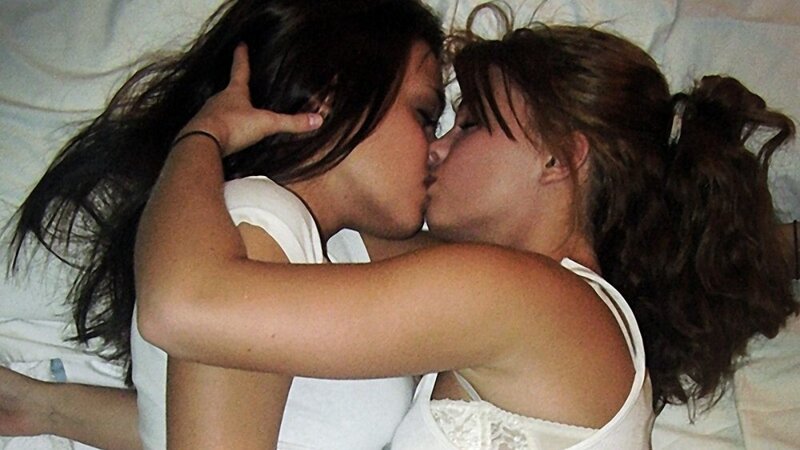 two women kissing on a bed