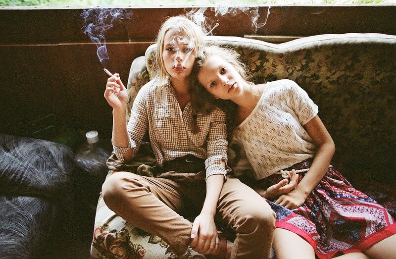 Two women on a couch with cigarette
