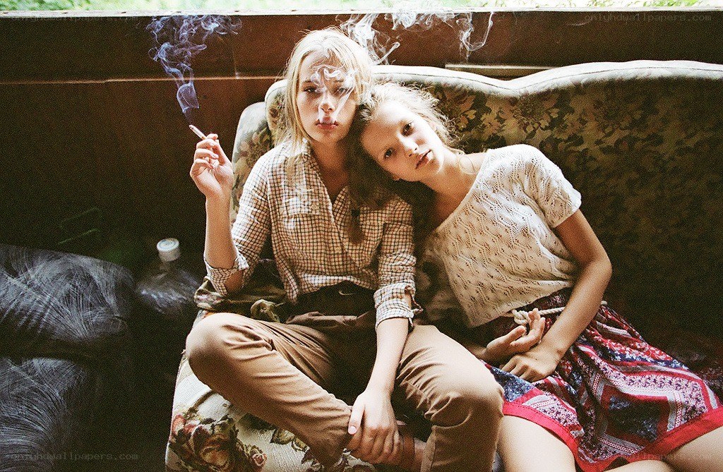 Two women on a couch with cigarette