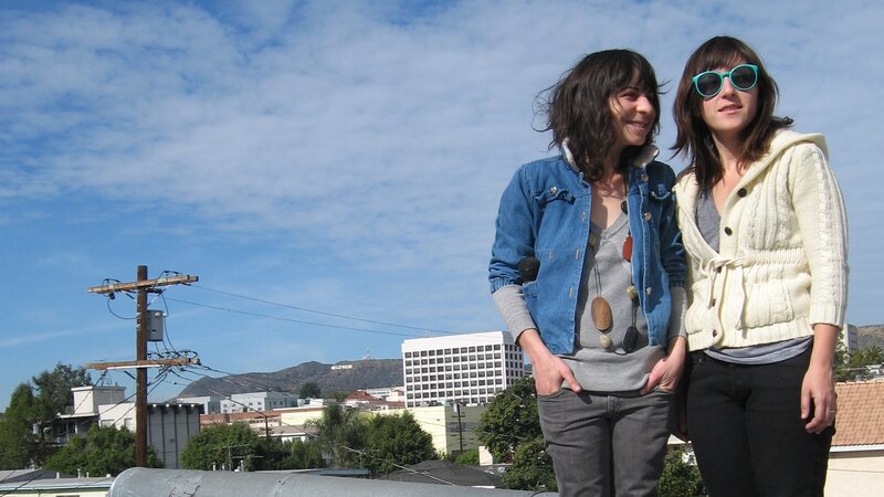 Two women on a rooftop with Hollywood sign