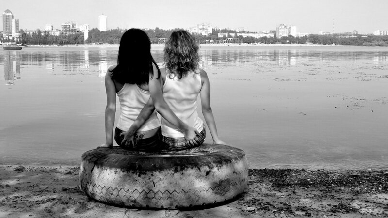 Two women on a tire by the water
