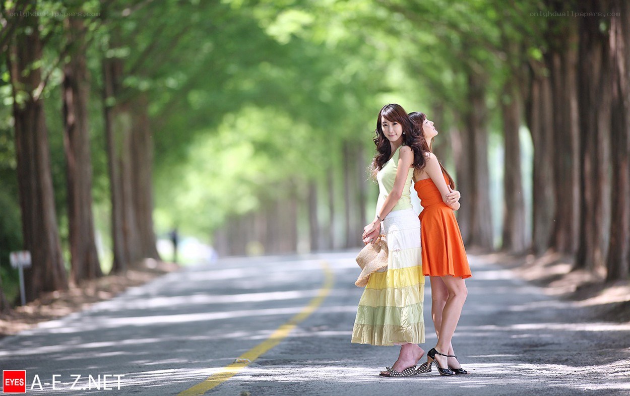Two women on a tree-lined road