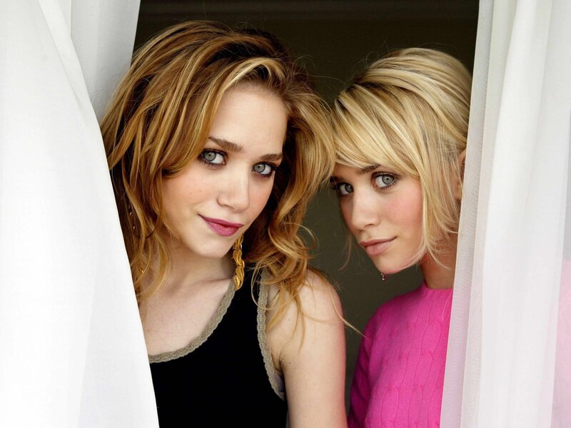 two women peeking from behind curtains