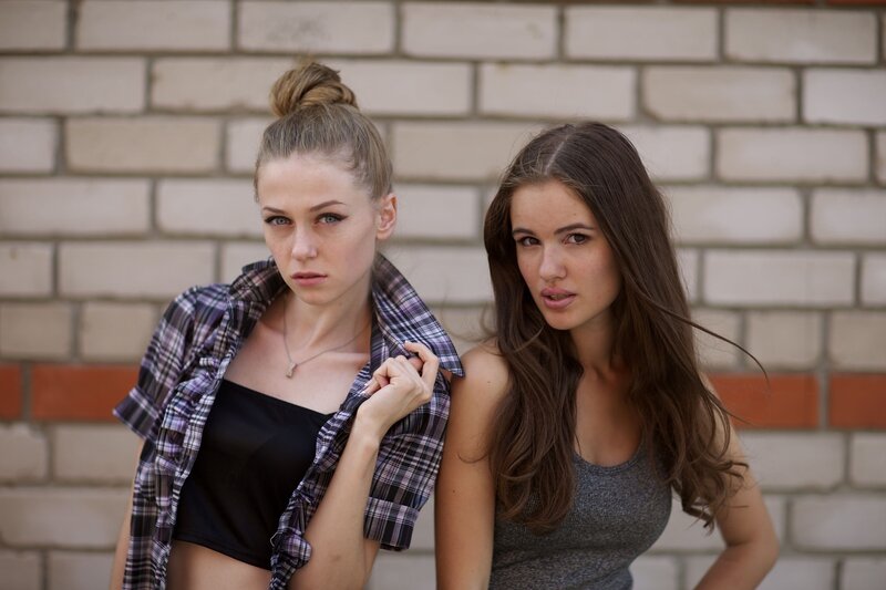Two women posing against a brick wall