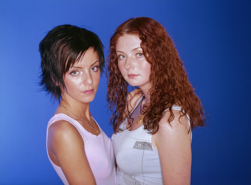 two women posing against blue background