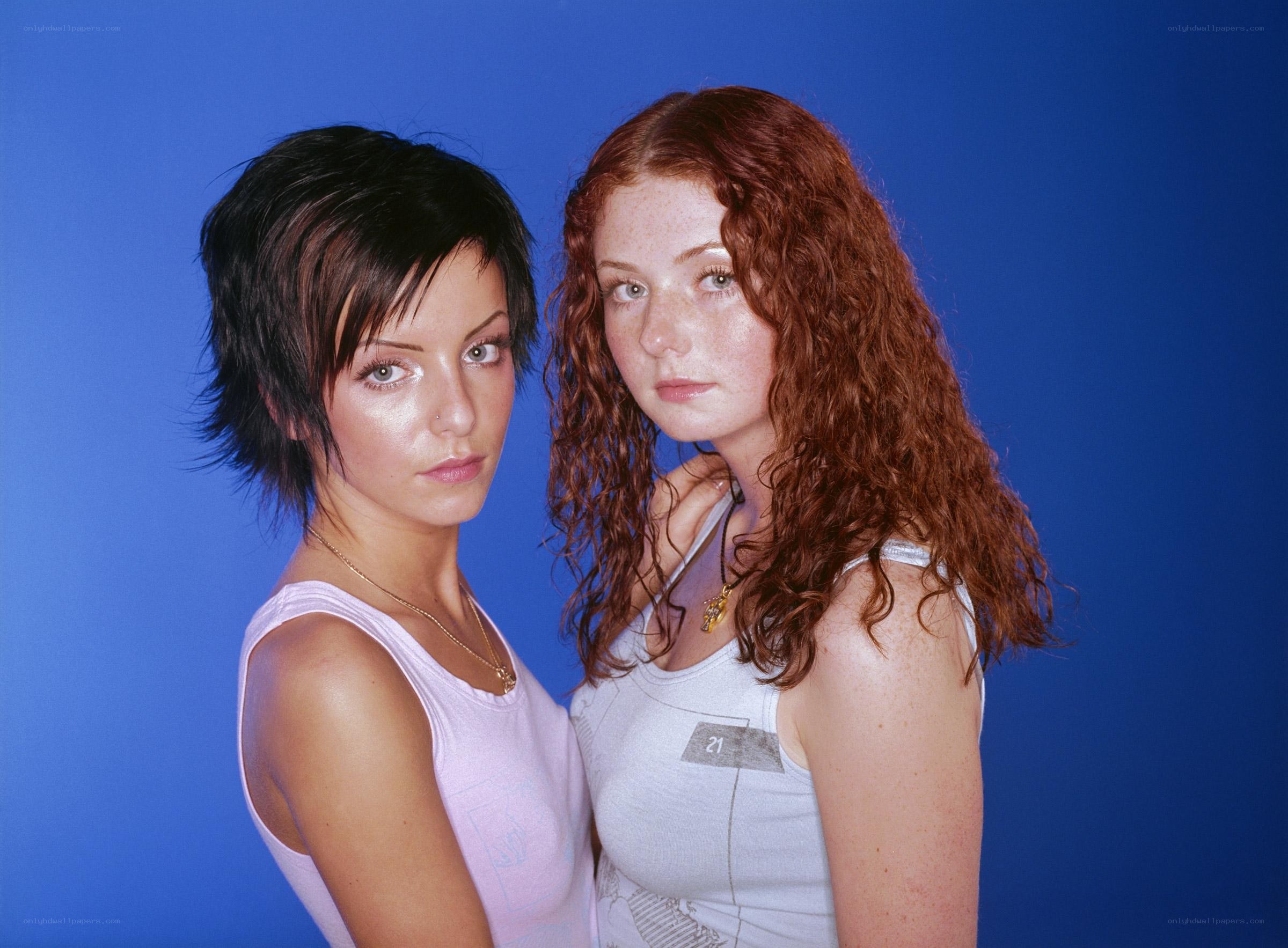 two women posing against blue background