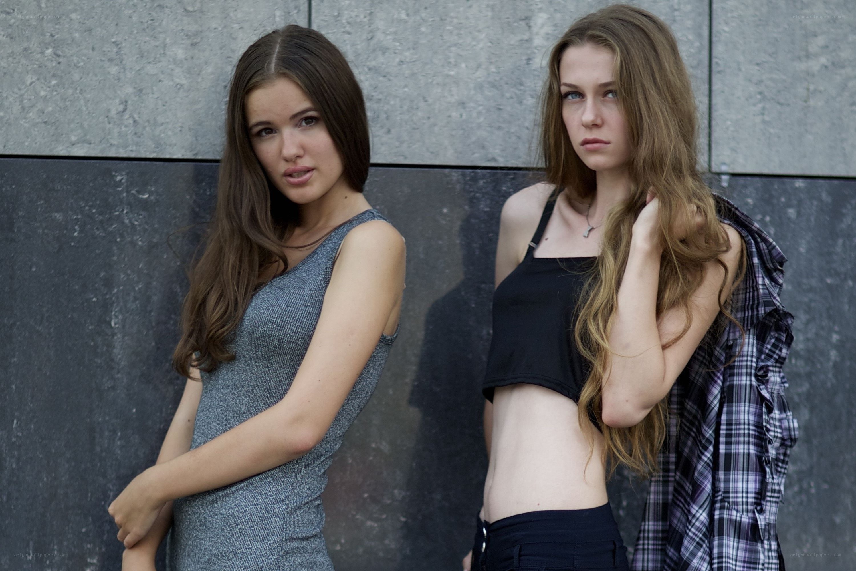 two women posing against wall