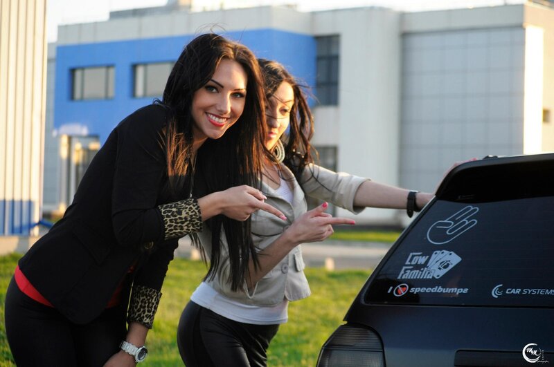 two women posing by a car