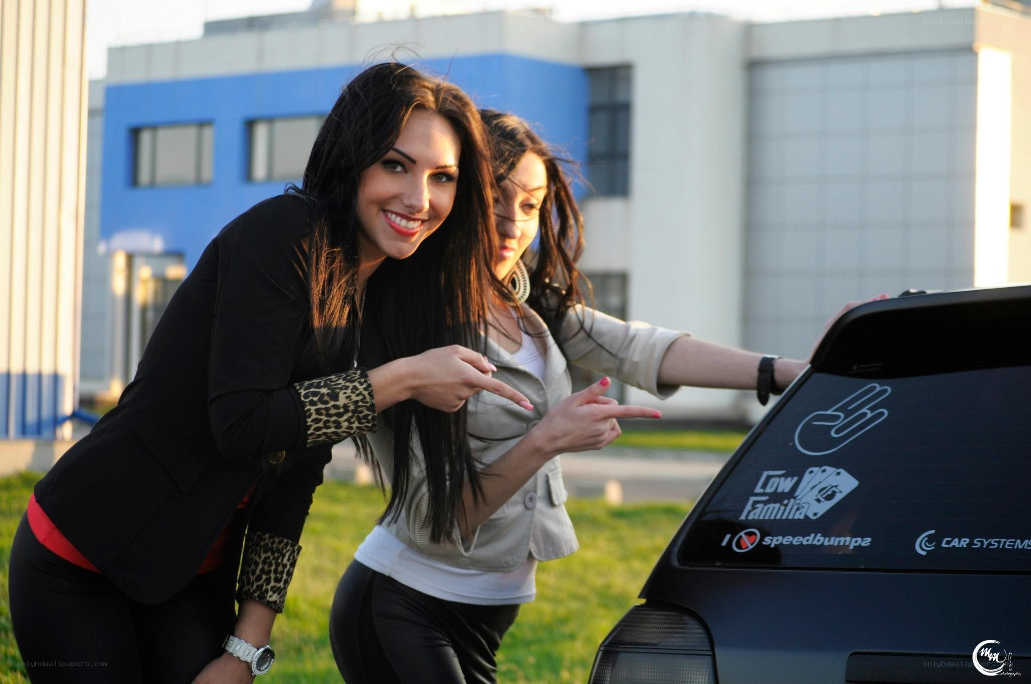 two women posing by a car