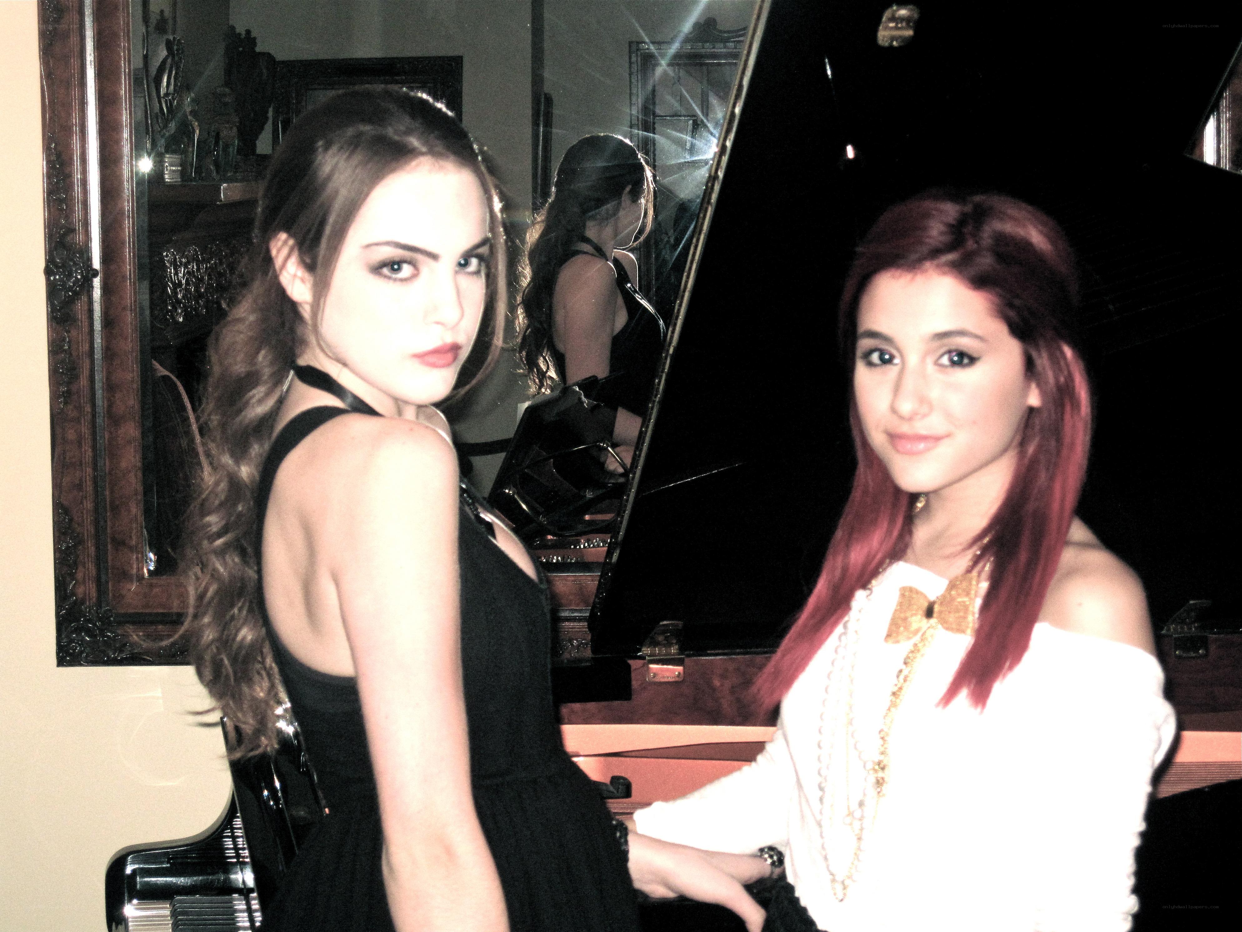 Two women posing by a piano