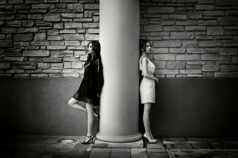Two women posing by a pillar