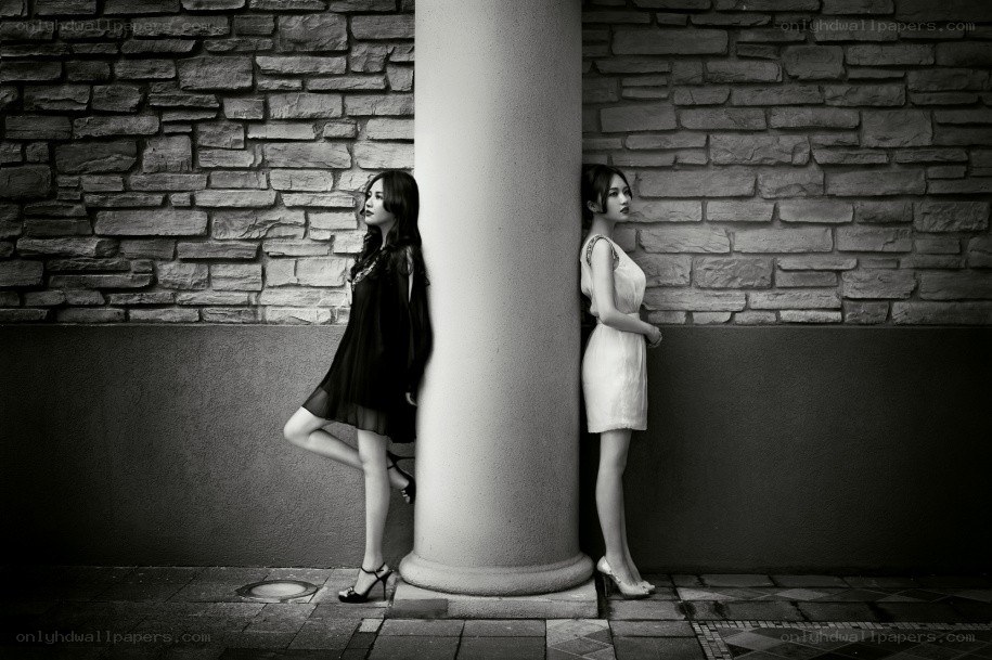 Two women posing by a pillar