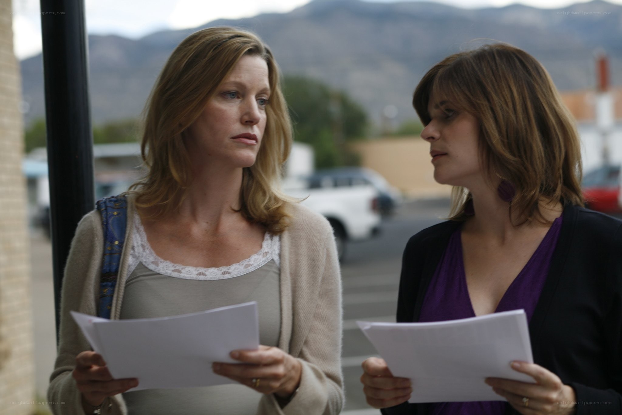 two women reading papers outside