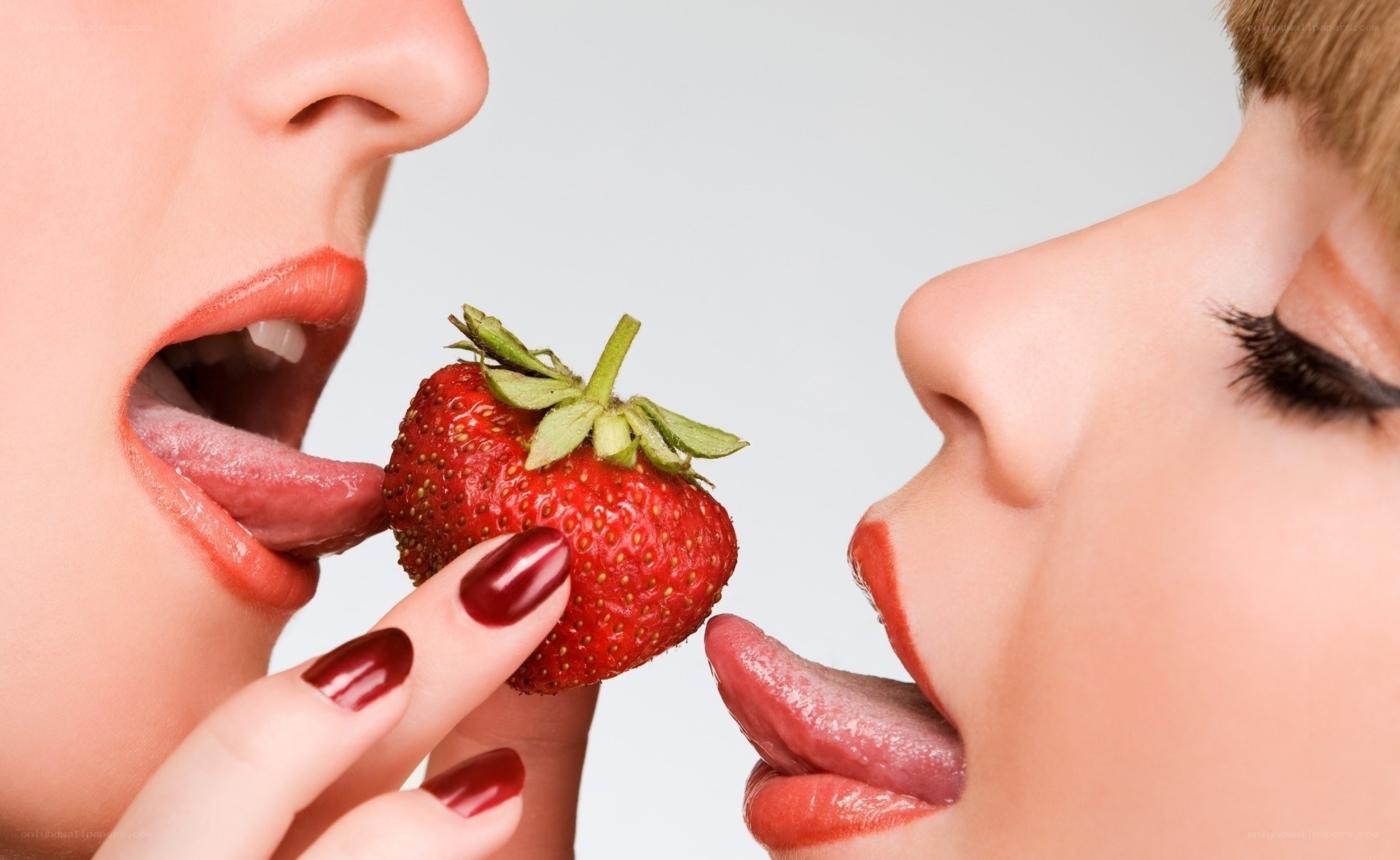 two women sharing a strawberry
