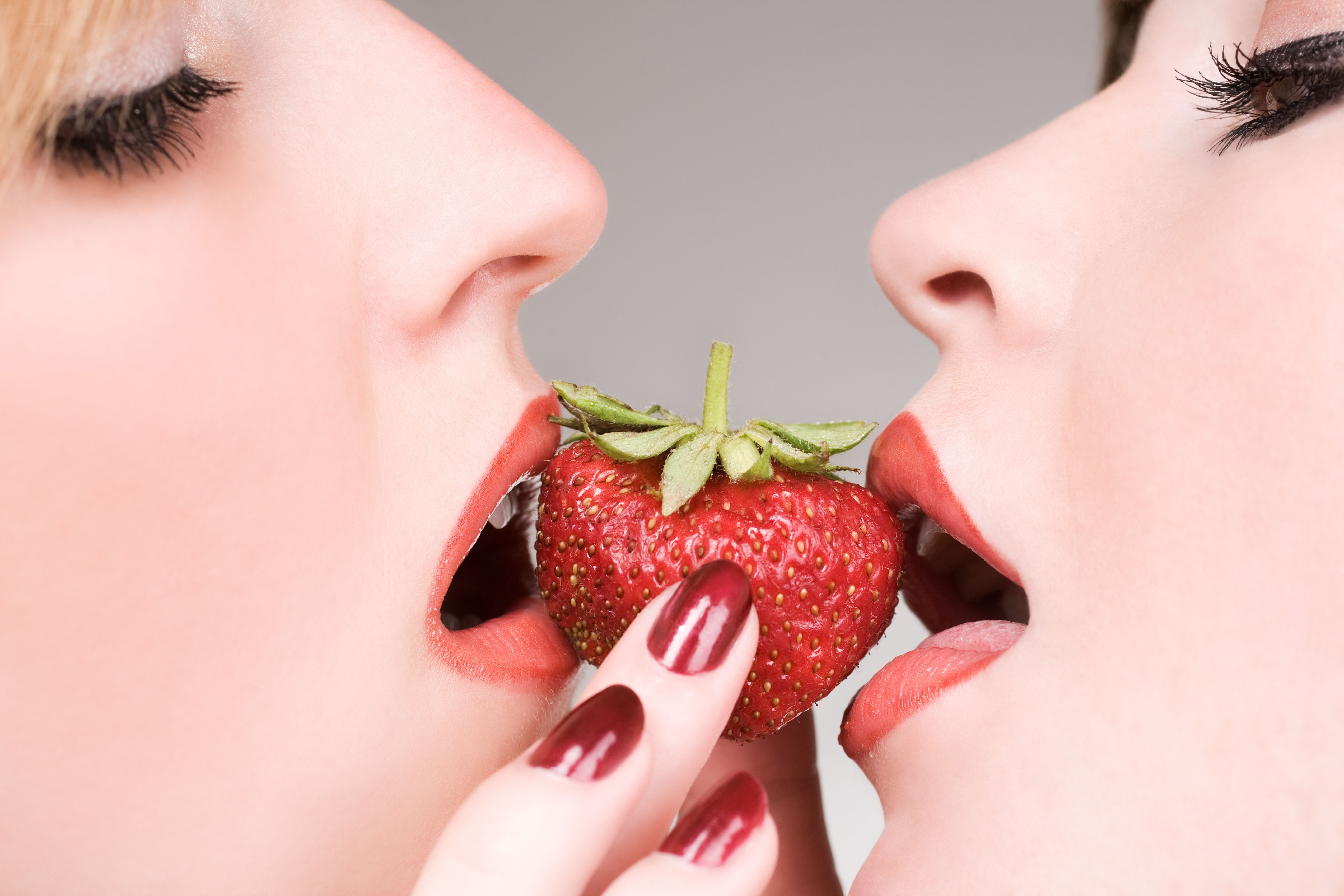 two women sharing a strawberry