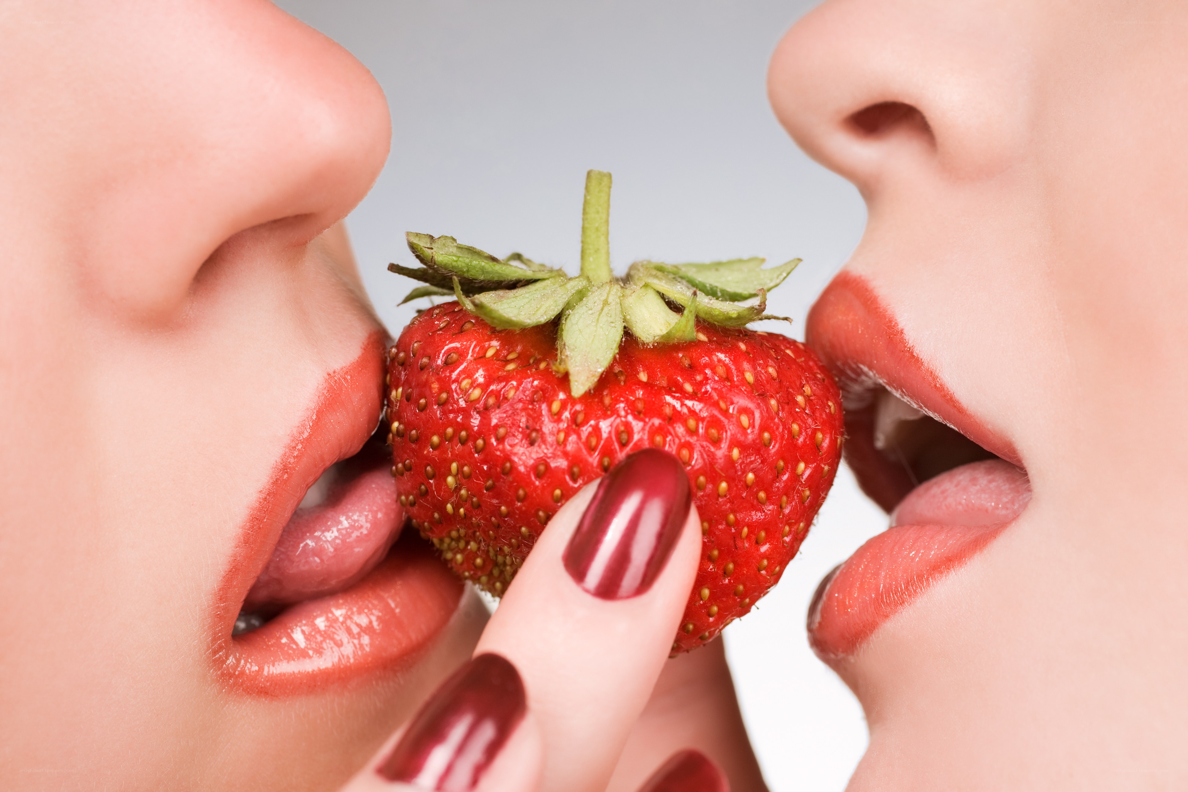 two women sharing a strawberry